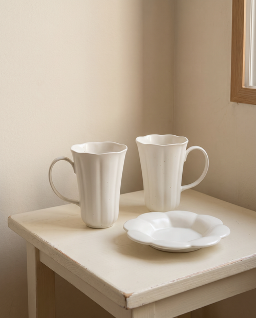Blooming mug and plate set by Insoil — three pieces on a painted side table by a window, the dessert hour for two