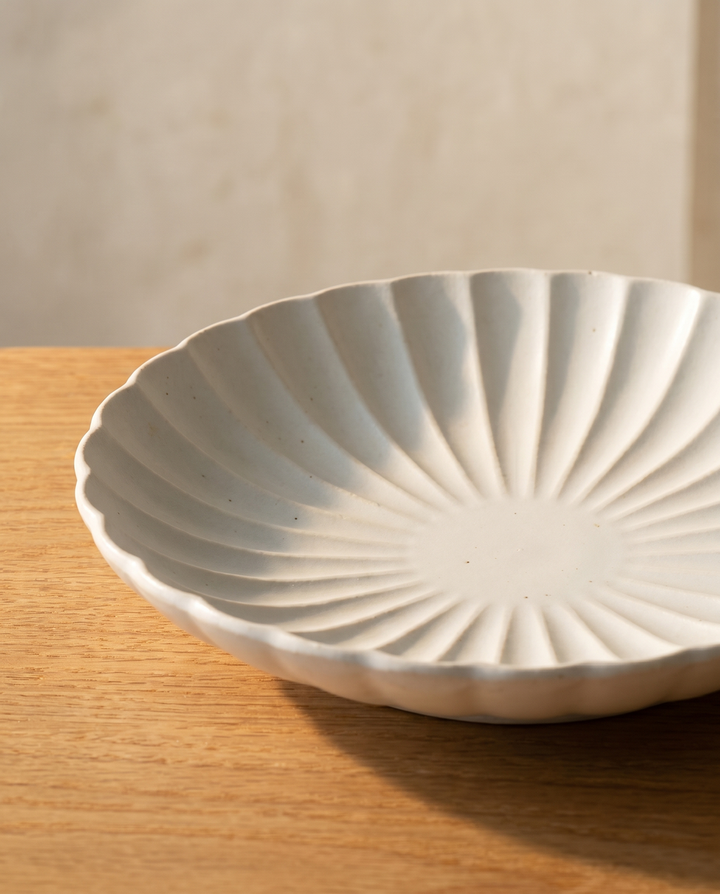 Flower plate set by Mujagi, the chrysanthemum plate's pleated rim in raking side-light