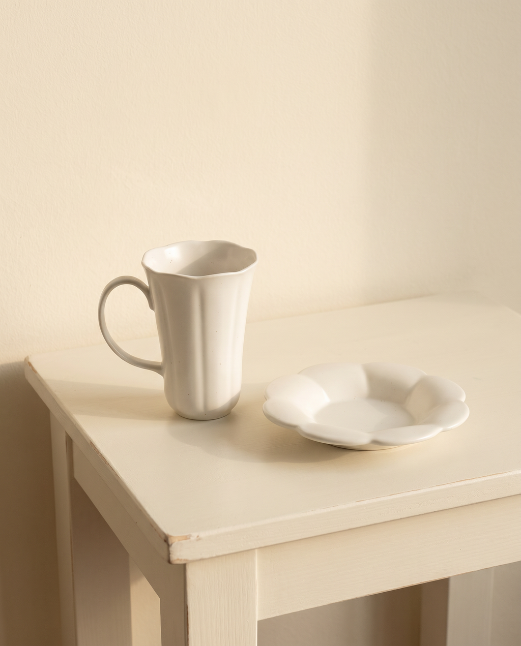 Blooming mug and plate set by Insoil — scale reference, plate beside one upright mug on a painted side table