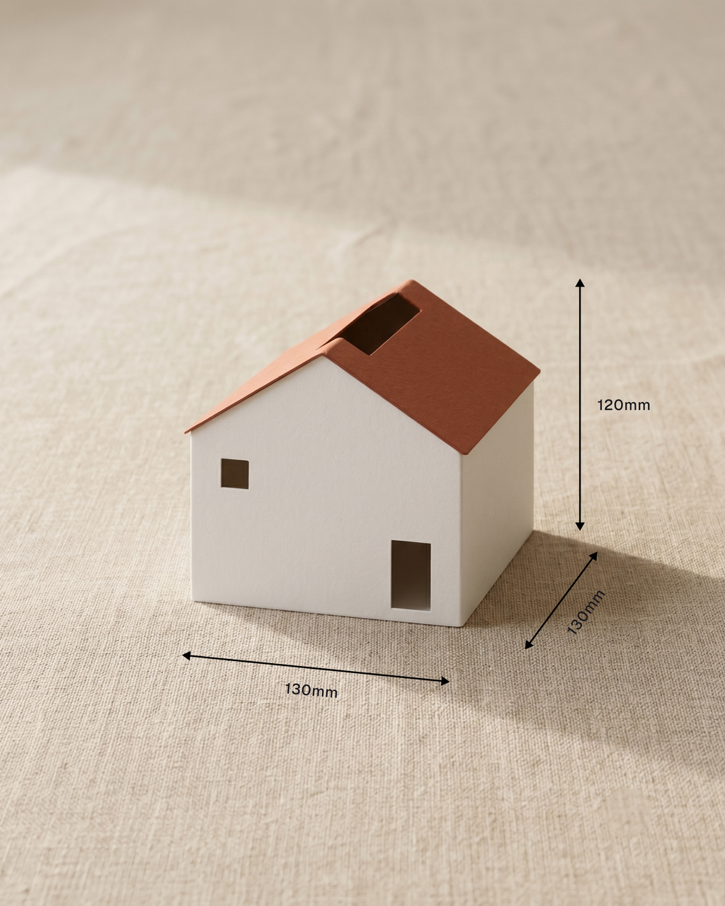 Small model house with dimensions indicated on a textured beige surface