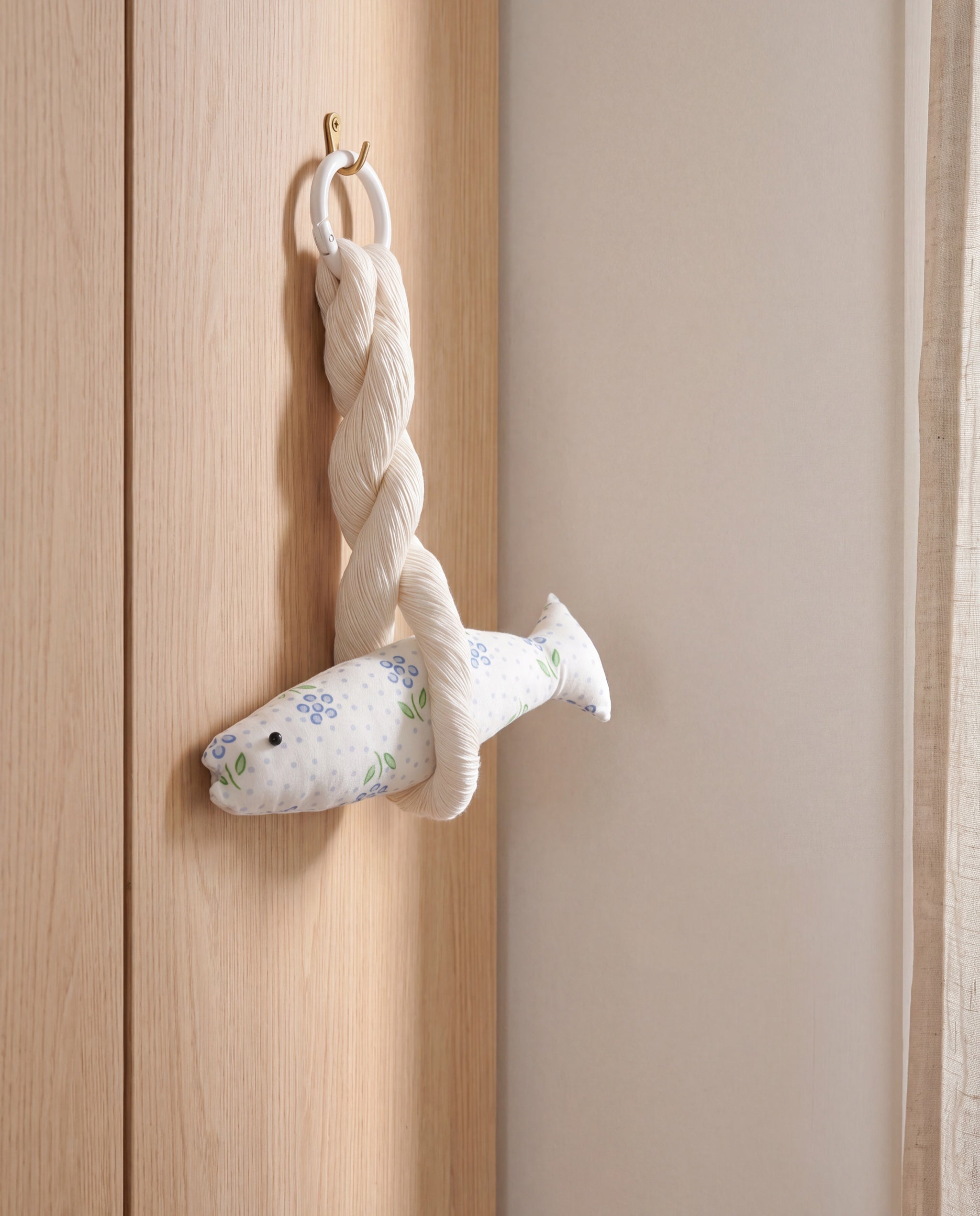 Blair good luck pollack ornament by lemonbaseball livingclub, hanging from a brass hook on a wardrobe door