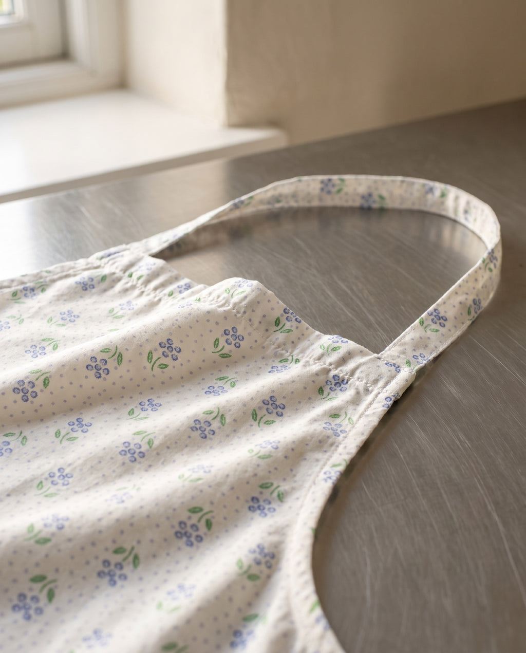 Close-up of the gathered bib top edge and the printed self-fabric neck strap