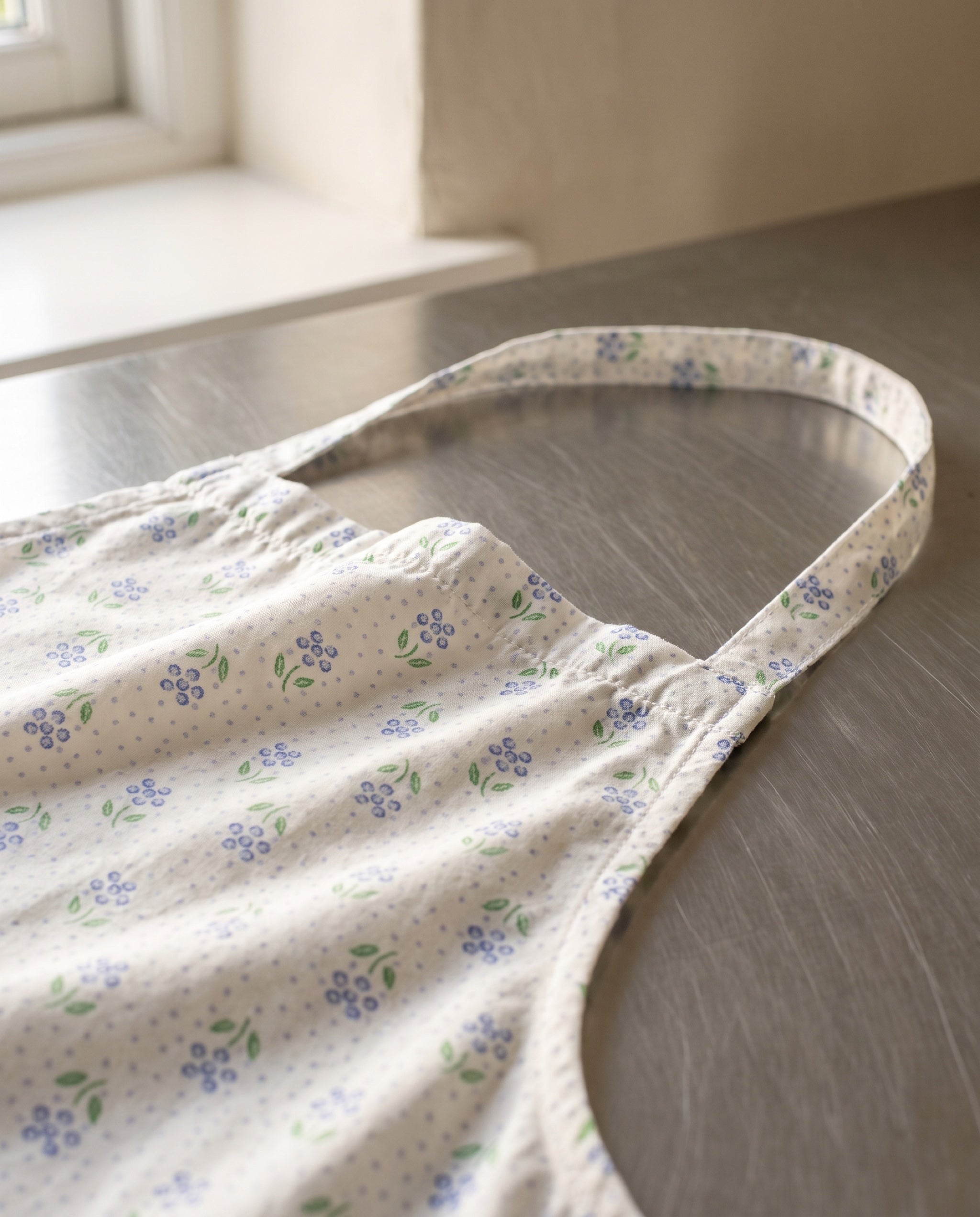 Close-up of the gathered bib top edge and the printed self-fabric neck strap