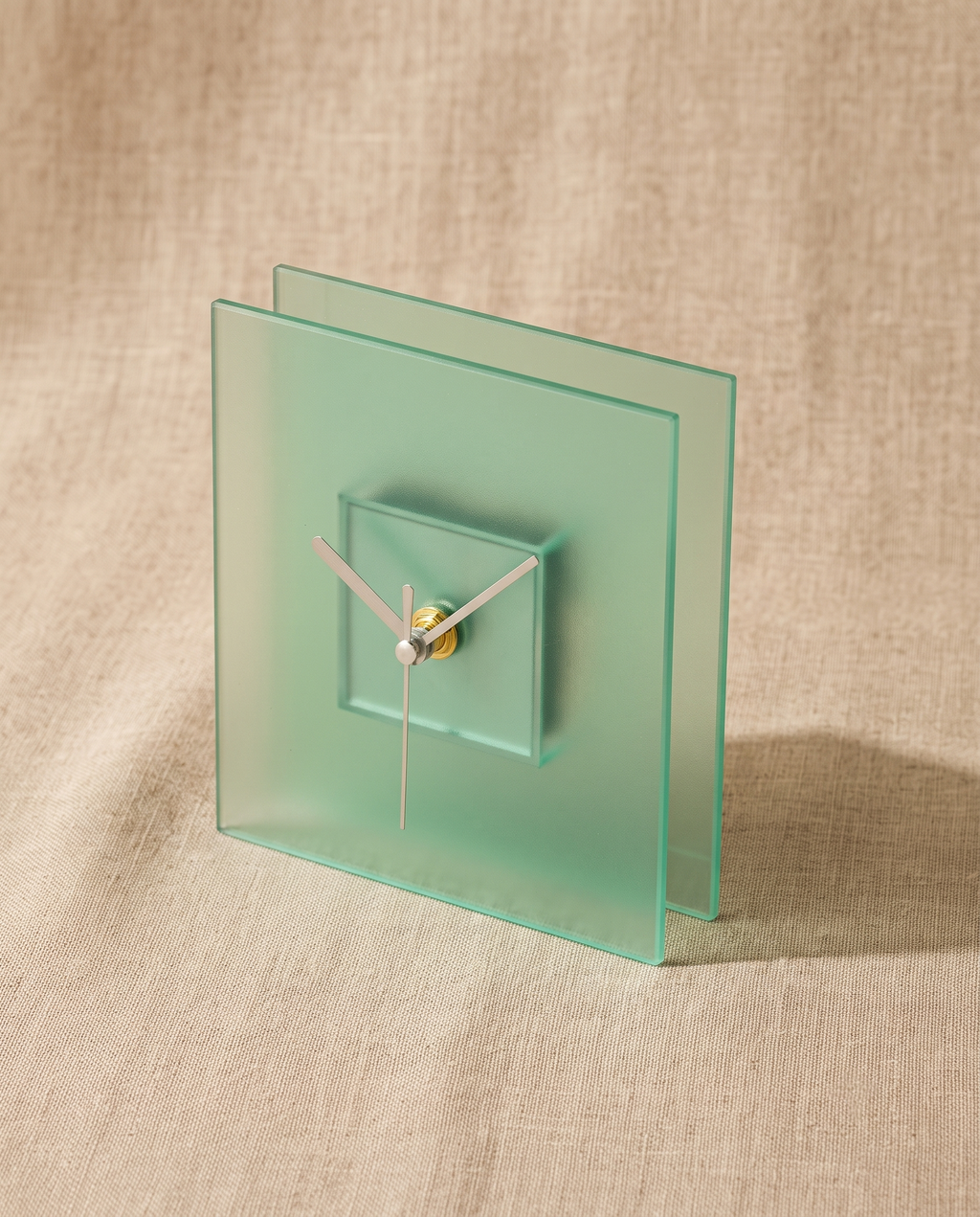 Block clock by APTONE in frosted green, three-quarter view on natural linen