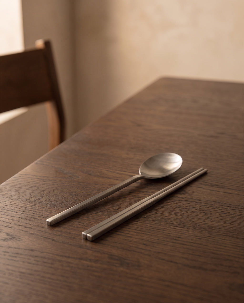 Essential dinner cutlery by NR Ceramics, set down at one place on a dark oak dining table