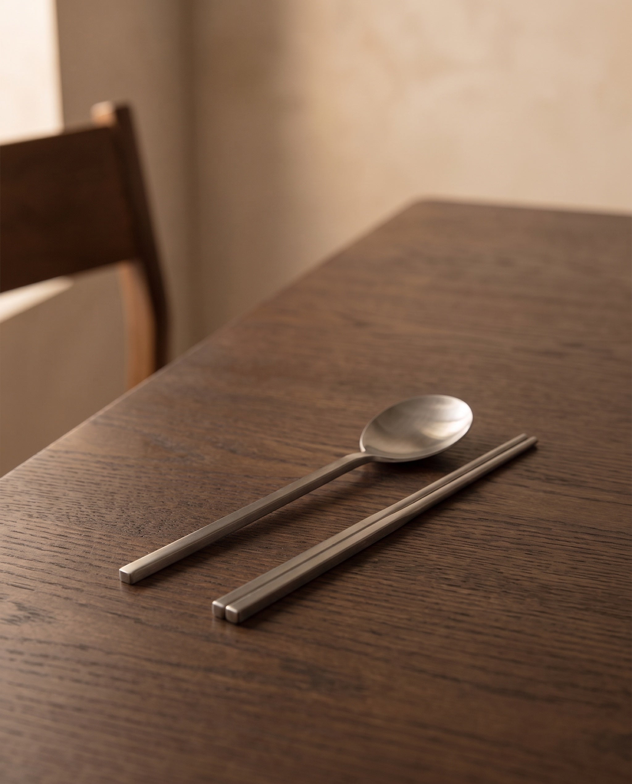 Essential dinner cutlery by NR Ceramics, set down at one place on a dark oak dining table