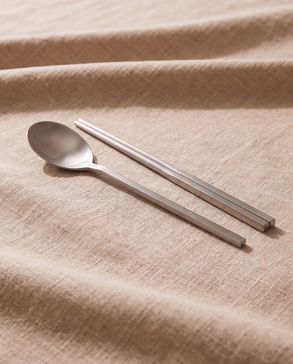 Essential dinner cutlery by NR Ceramics, semi-matte brushed steel on beige linen
