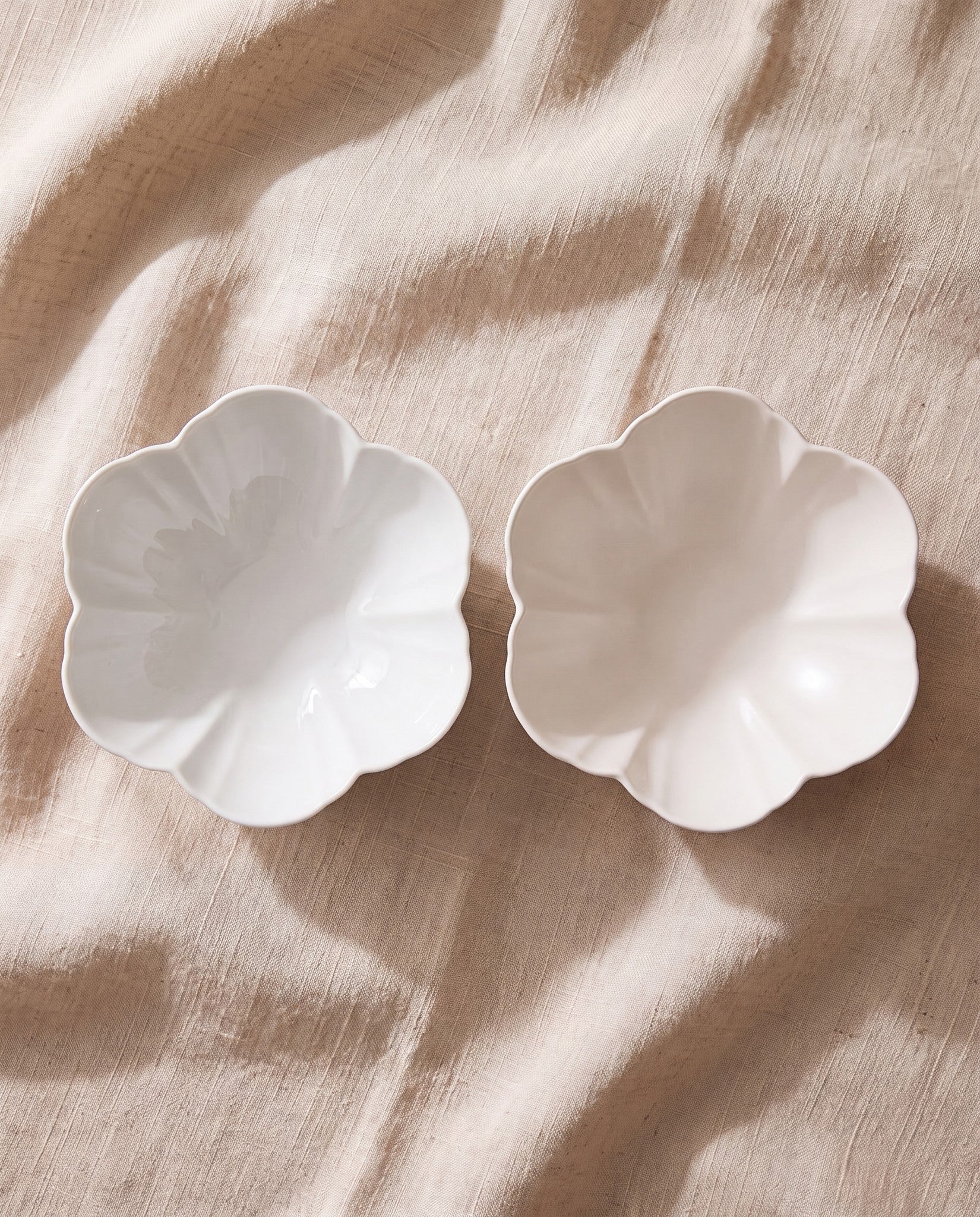Two Mujagi Flower 06 round bowls in white porcelain on beige linen