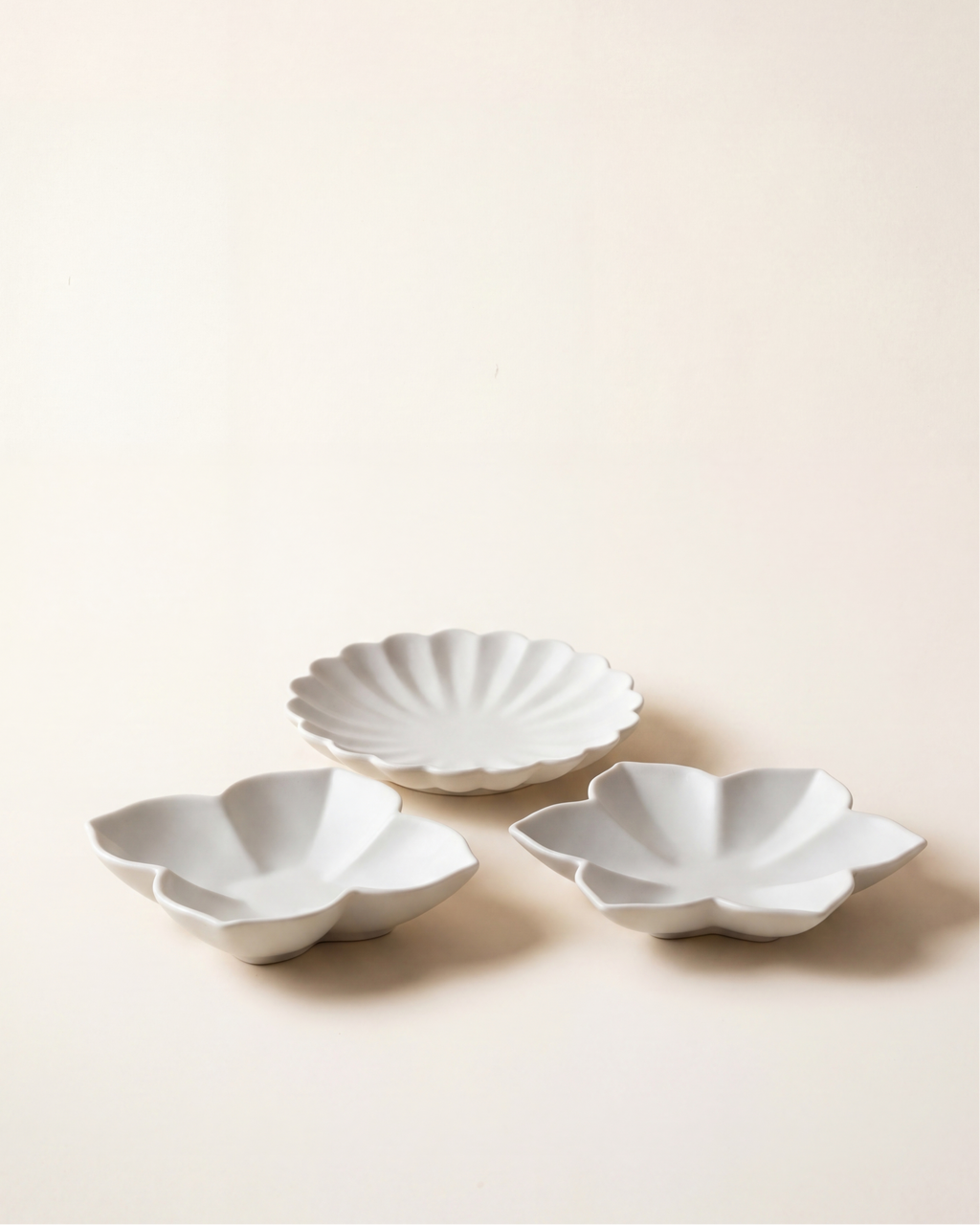 Flower plate set by Mujagi, hand-formed Korean baekja porcelain in three petal forms on a hanji-cream backdrop