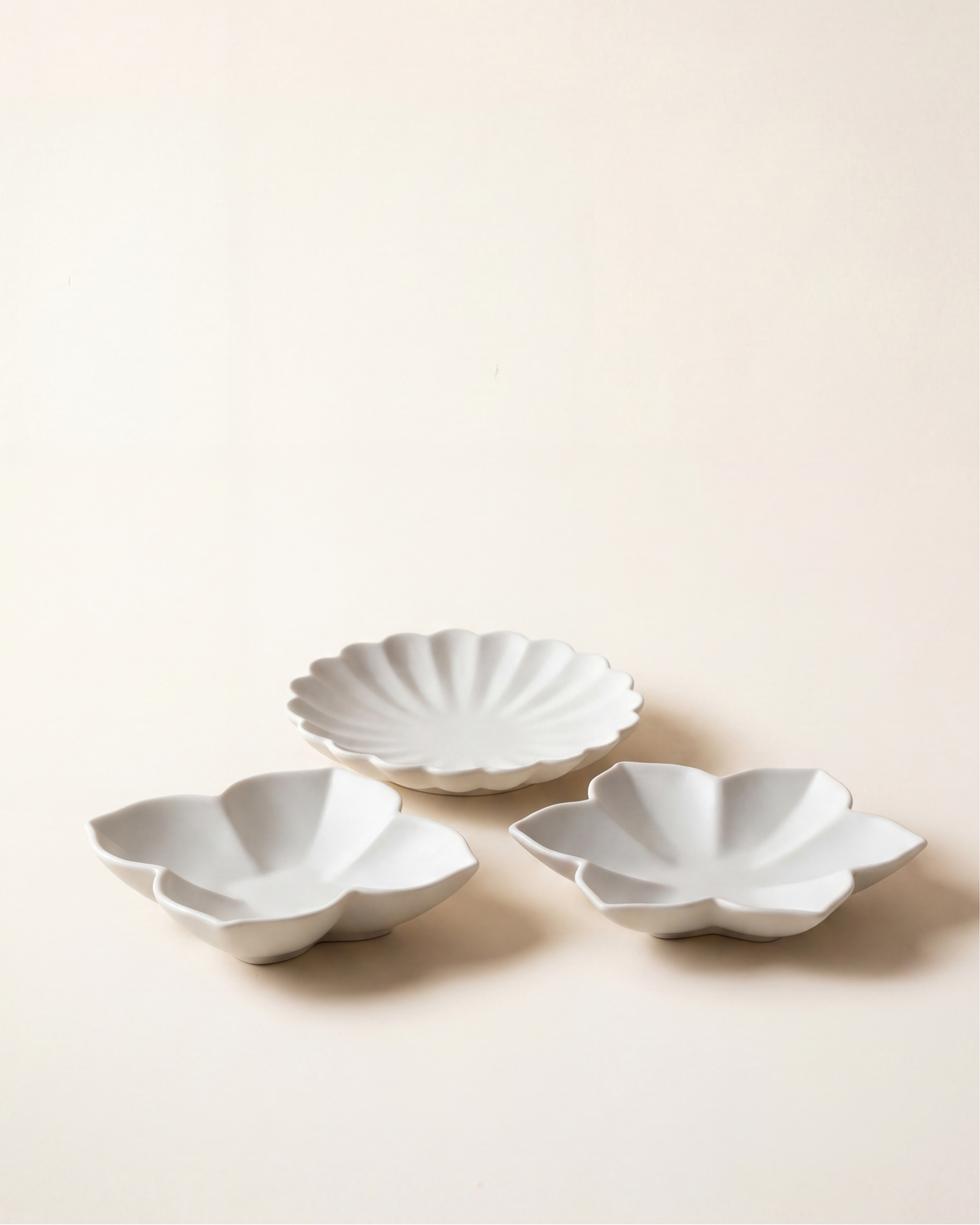 Flower plate set by Mujagi, hand-formed Korean baekja porcelain in three petal forms on a hanji-cream backdrop