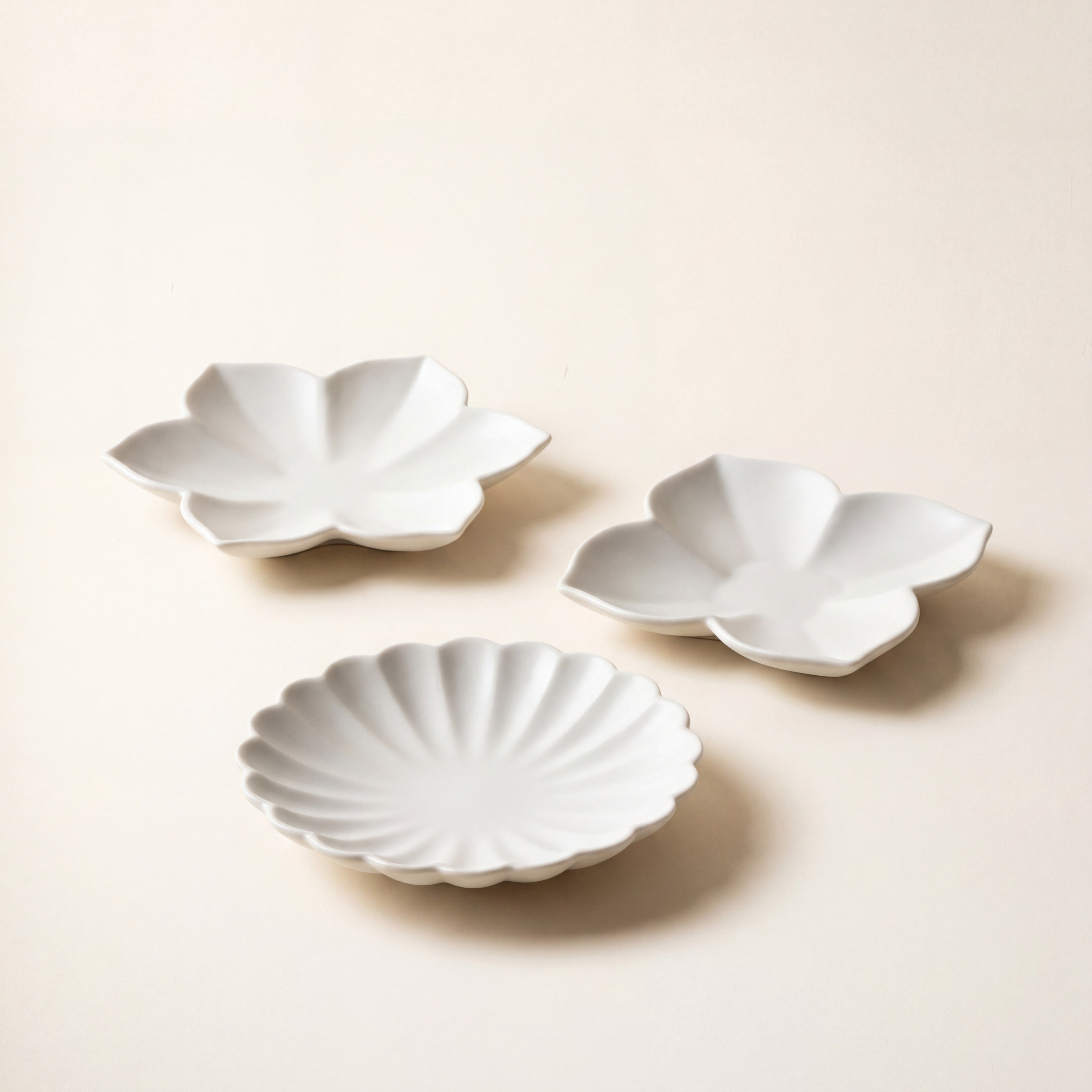 Flower plate set by Mujagi, hand-formed Korean baekja porcelain in three petal forms on a hanji-cream backdrop