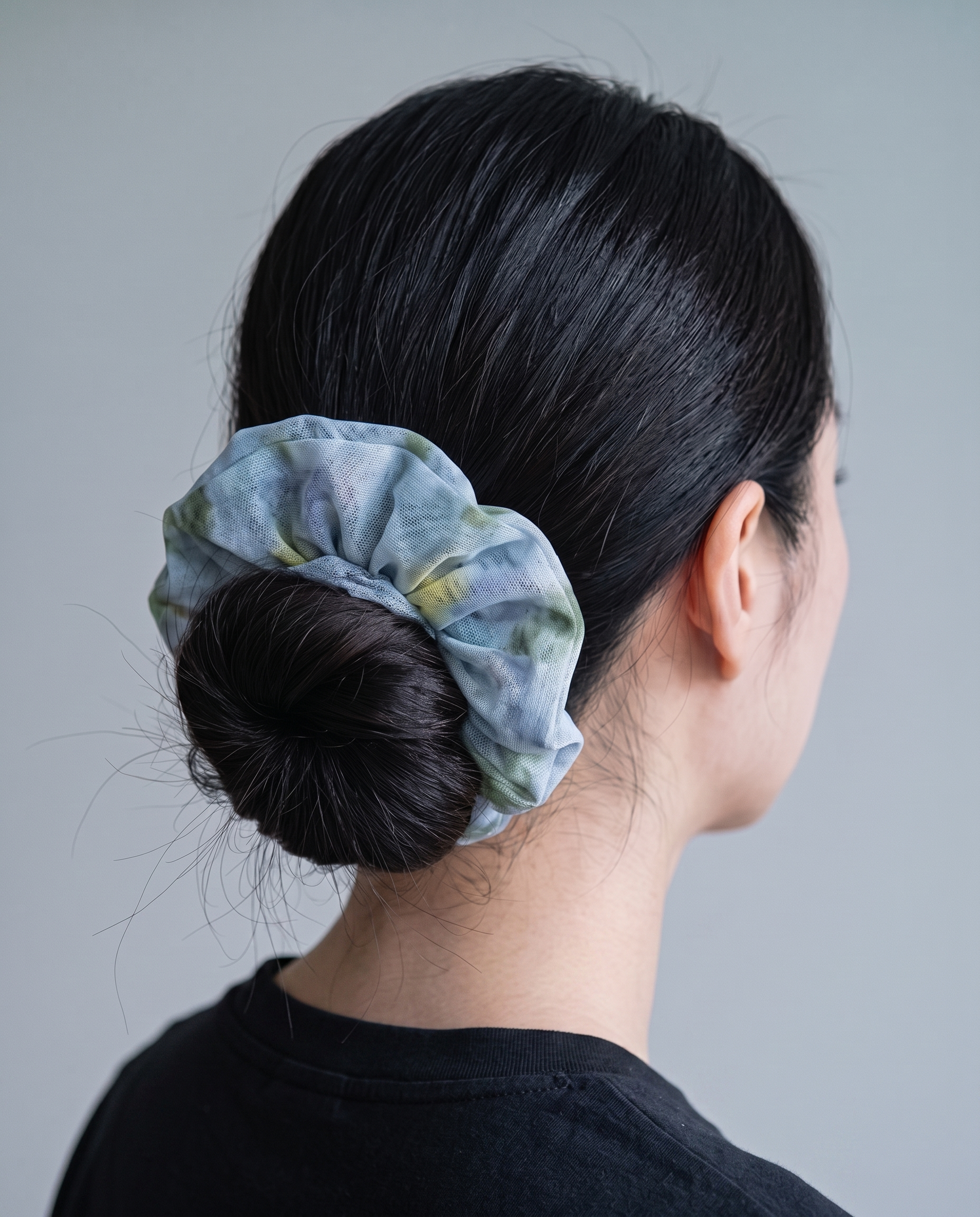 Misty blue scrunchie worn in a low bun