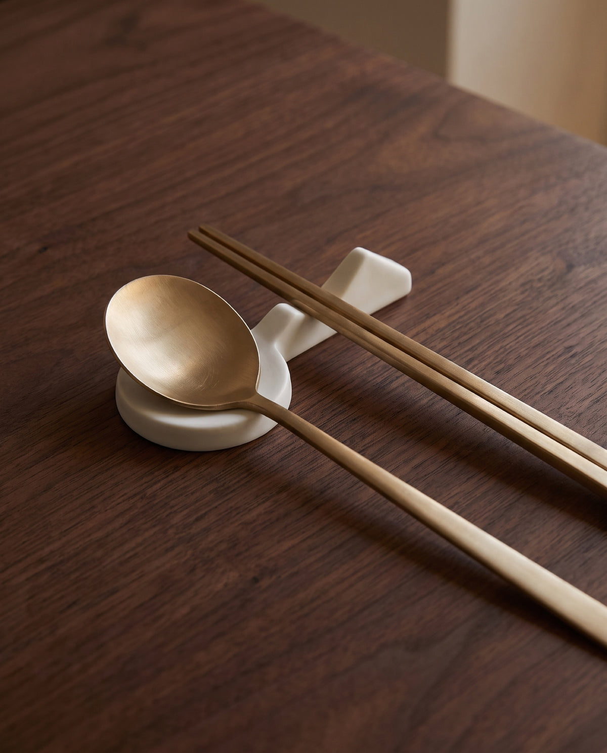 Land scape cutlery rest by Mujagi, holding a brass spoon and chopsticks