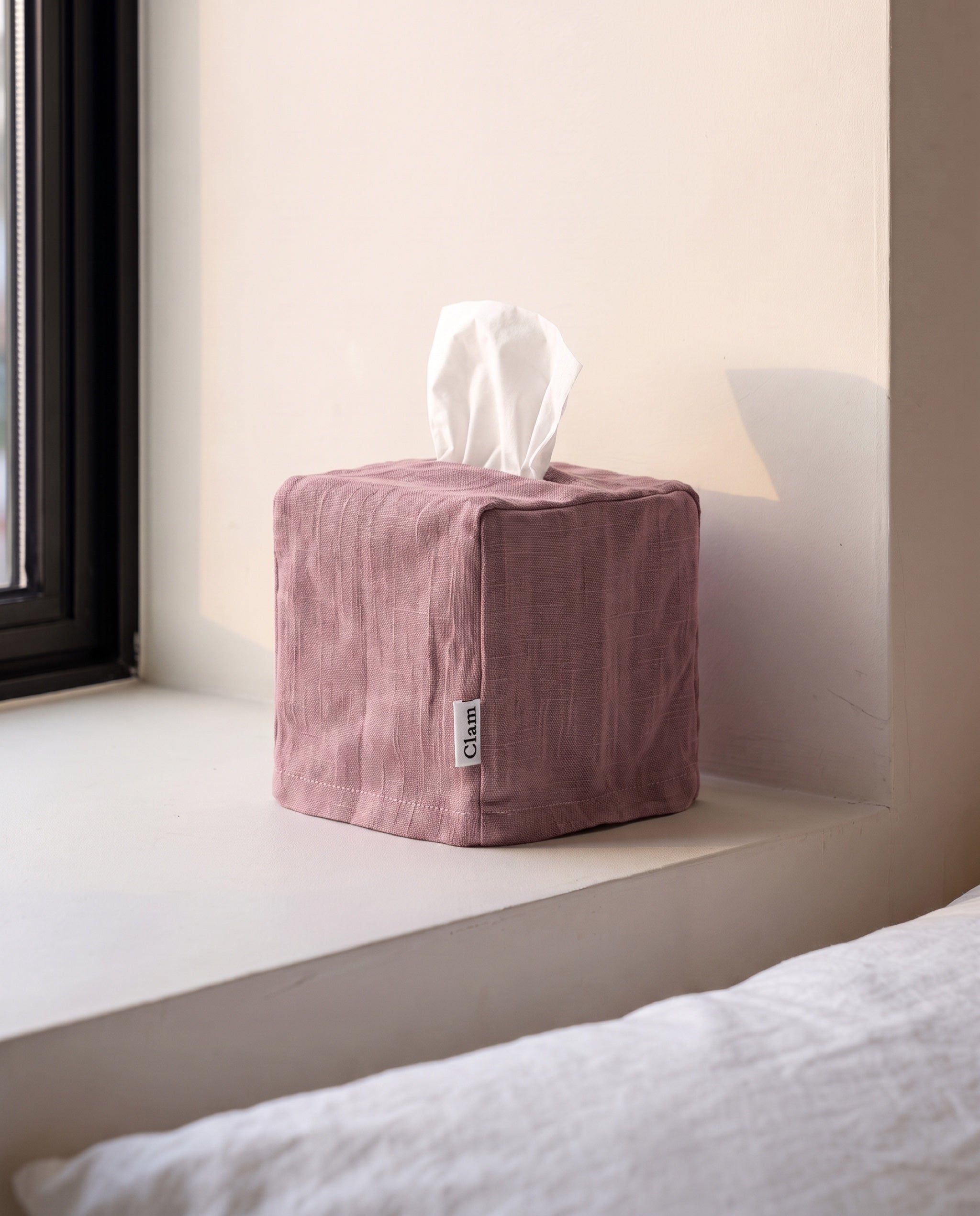 Linen tissue cover by Clam in Baby pink, a dusty mauve rose, on a bedroom window sill