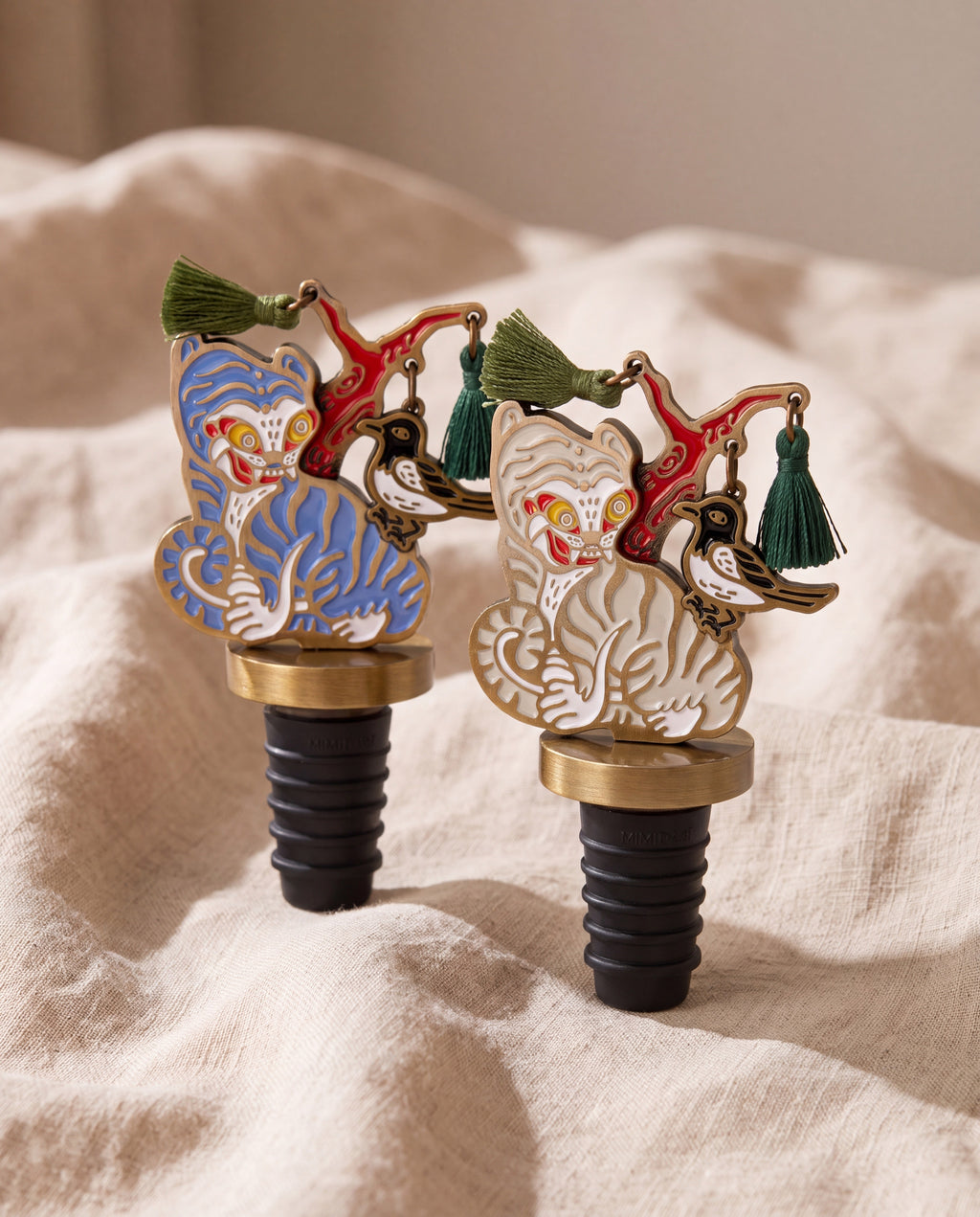 Magpie and tiger wine stopper by Mimidar, both colorways on beige linen