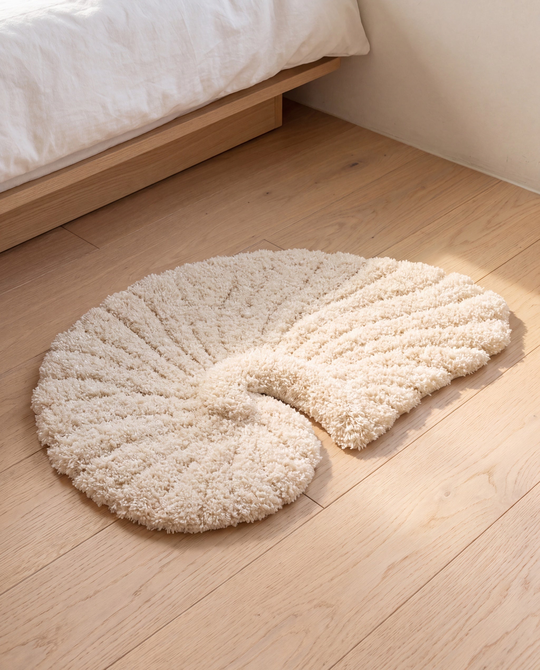 Poh object rug by Lug Lug, on pale oak floorboards beside a low bed