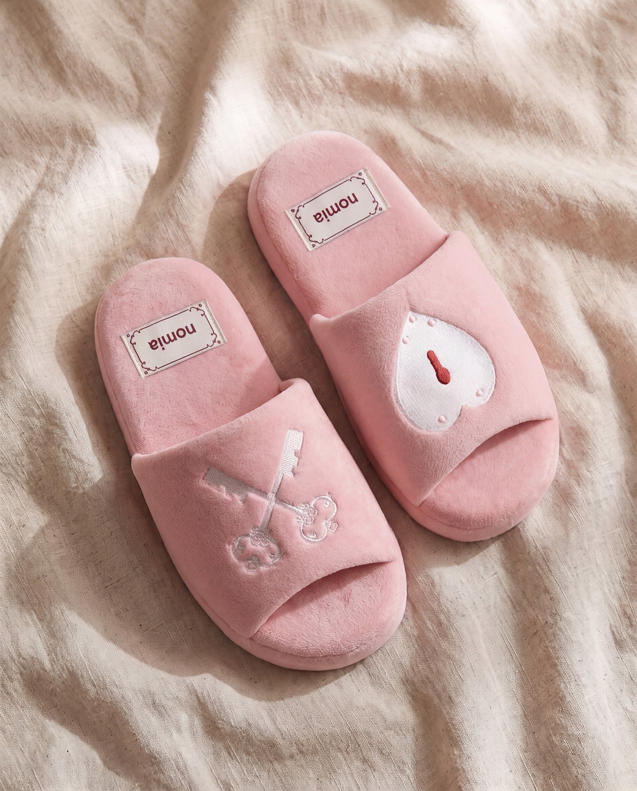 Secret rosy microfiber room shoes by Nomia, a pair on beige linen