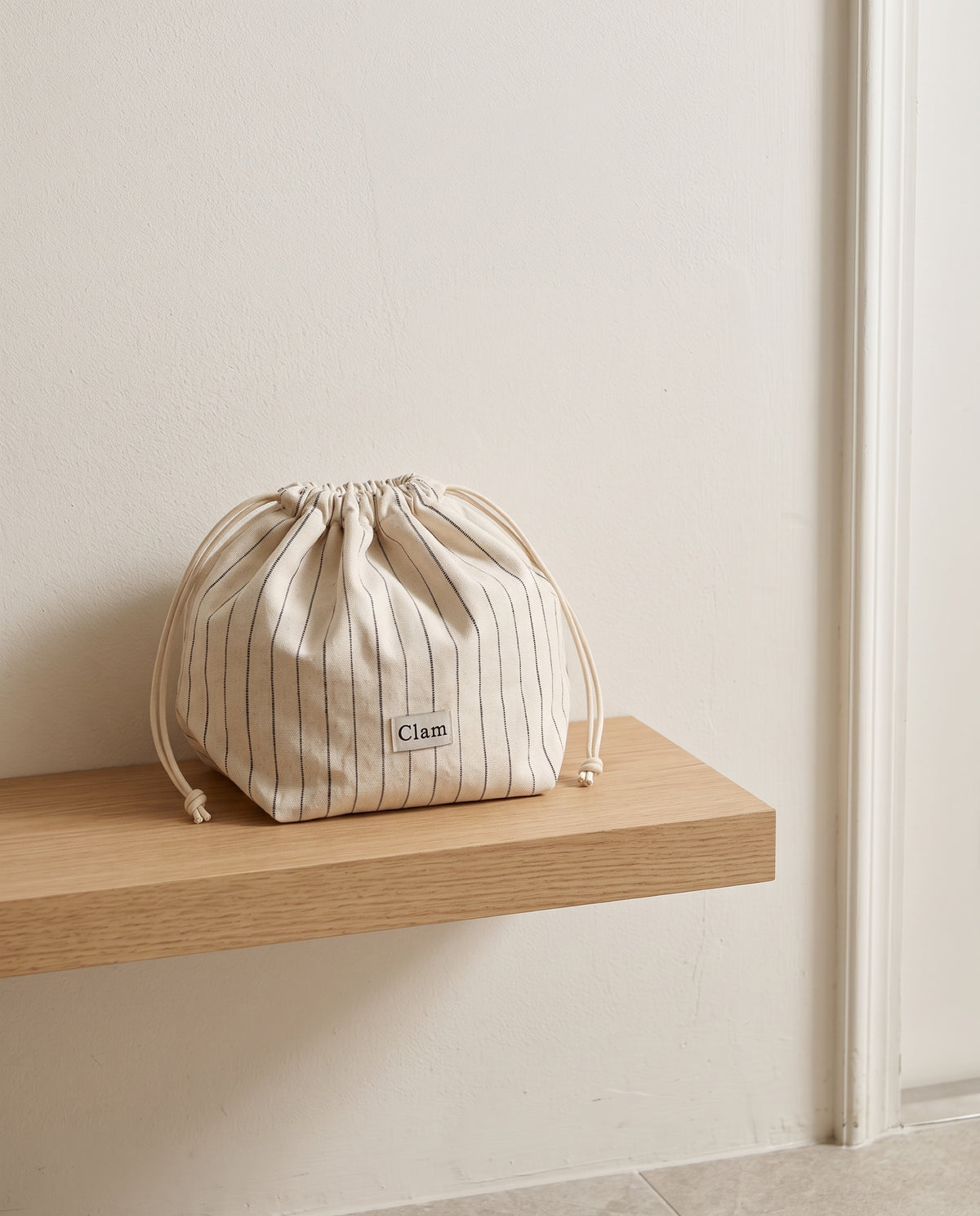 String pouch by Clam, packed and cinched on an entryway shelf