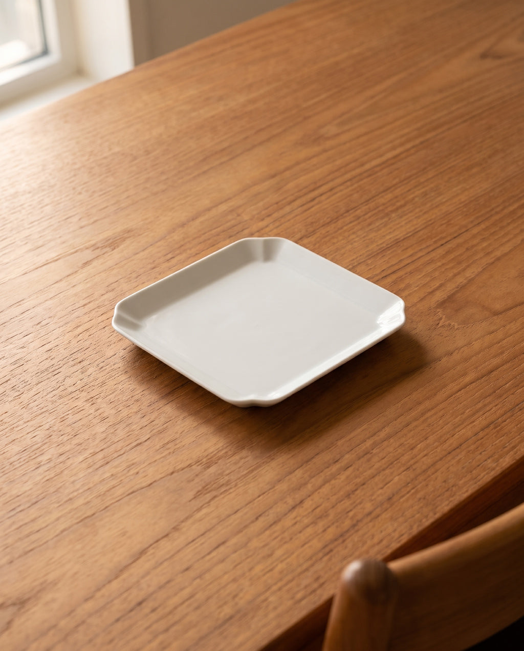 Square plate by Mujagi, the medium size on an oiled teak dining table