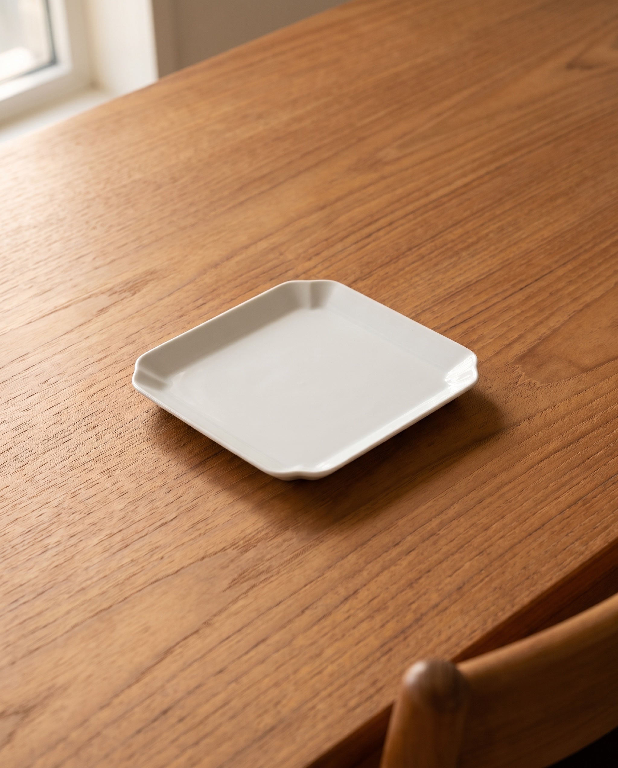 Square plate by Mujagi, the medium size on an oiled teak dining table