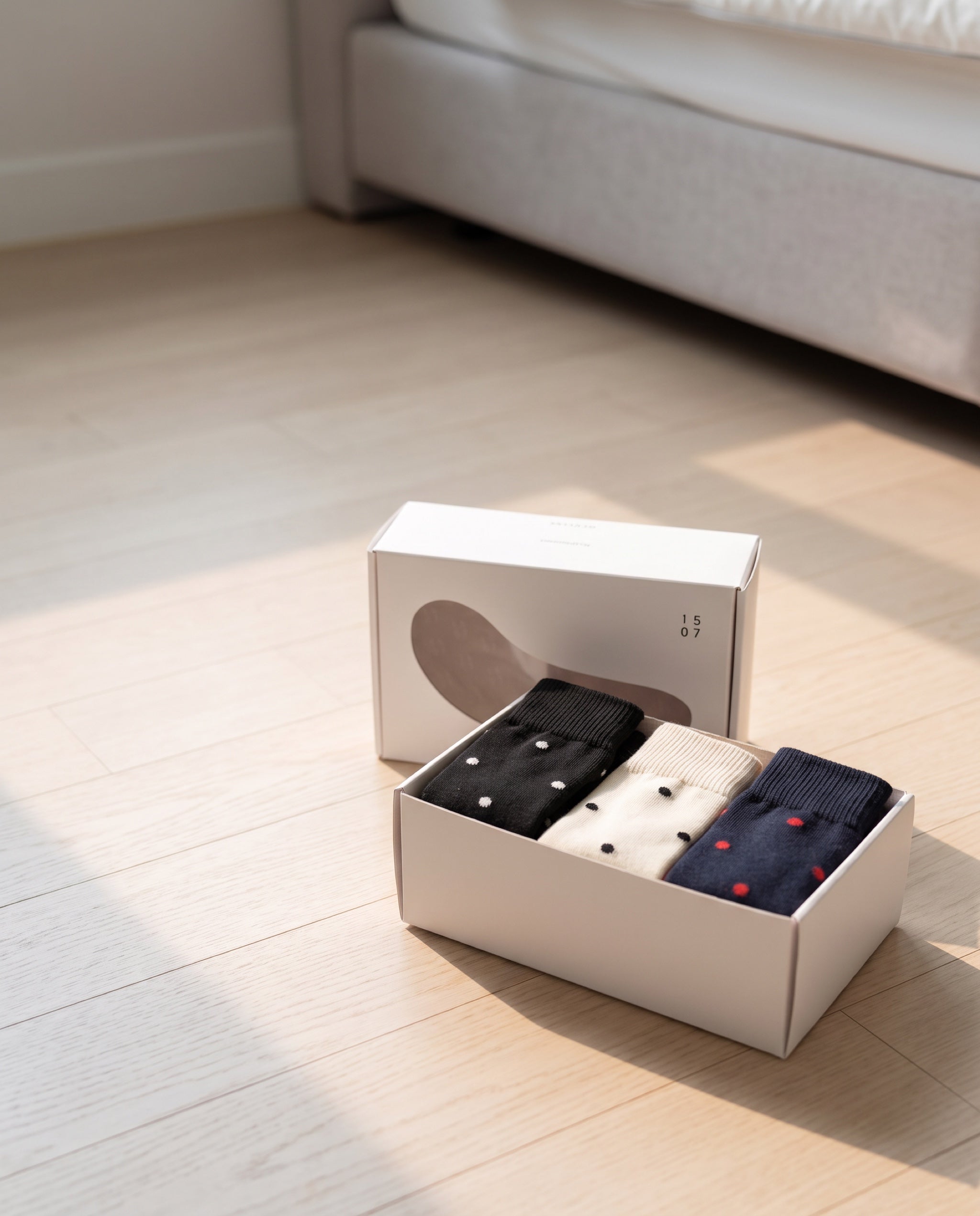 Unisex dot basic socks by 1507, the box opened on a bedroom floor, lid leaning behind it