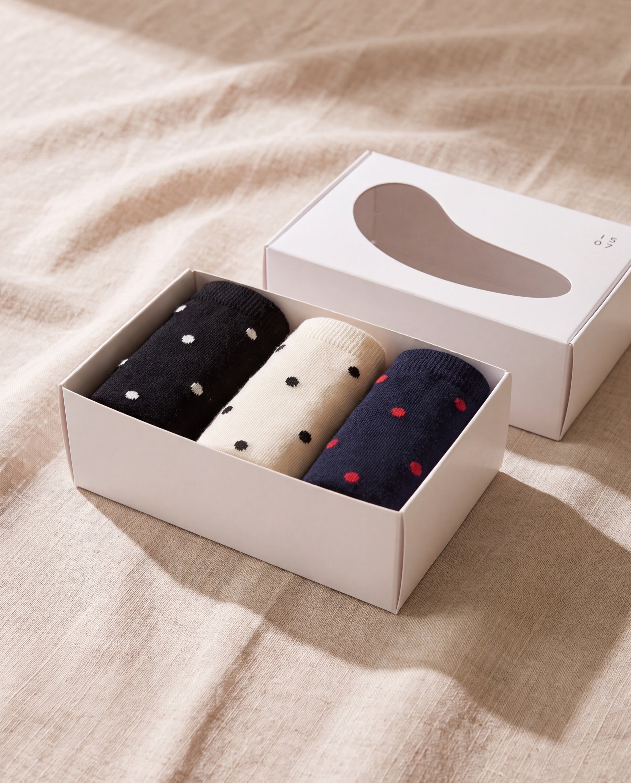 Unisex dot basic socks by 1507, the open gift box with three pairs, on beige linen