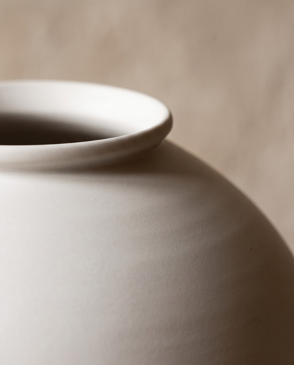 Macro of the rolled rim and matte white shoulder of the moon jar